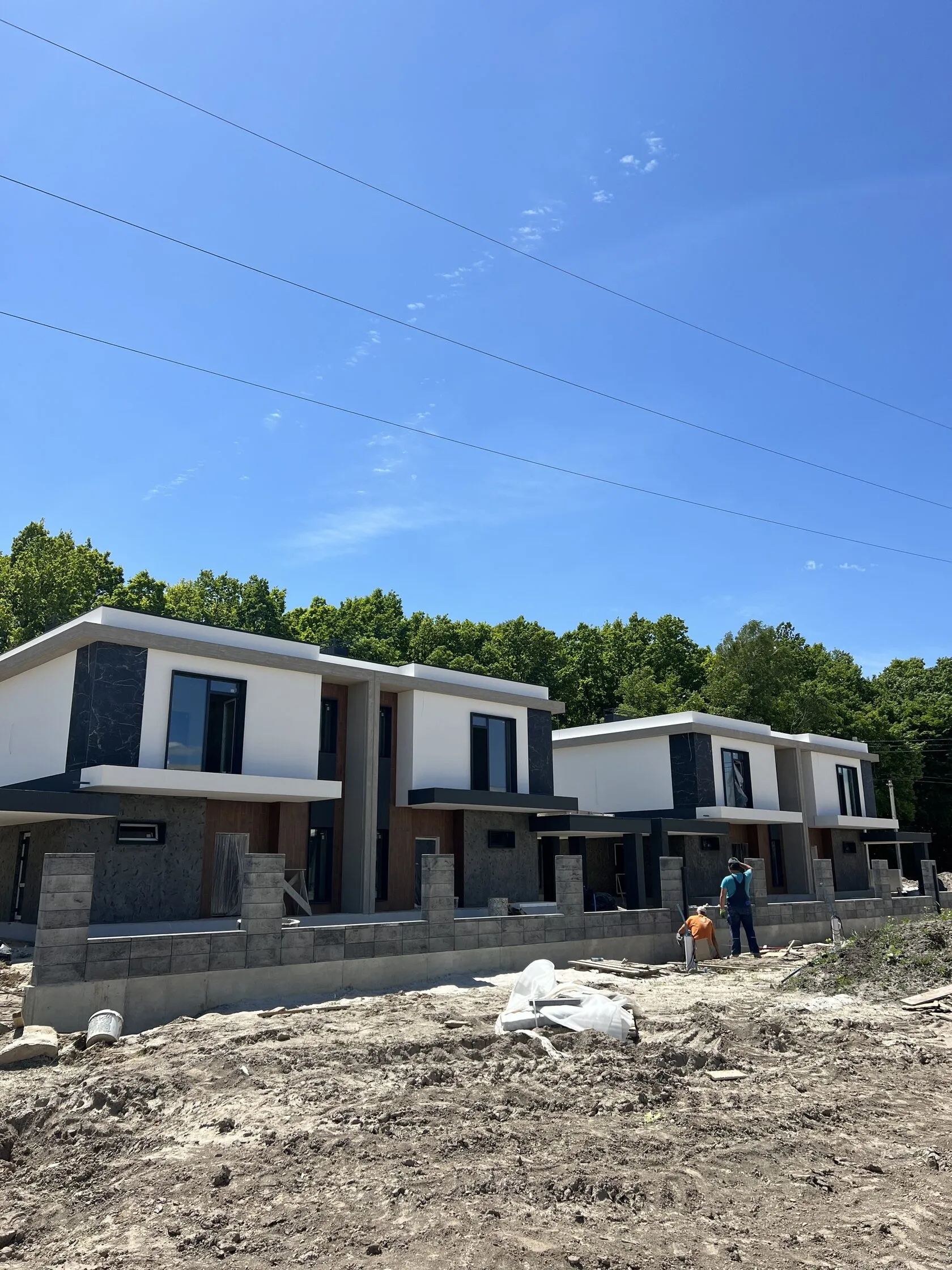 Архівне фото забудовника, квітень 2024: ряд зведених дуплексів Stone Village на тлі лісу